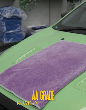 A purple car drying towel folded on a green car